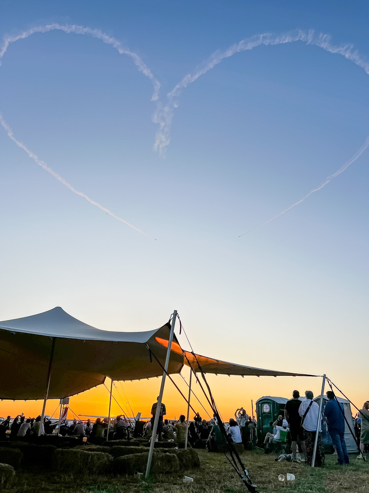 Display smoke drawn into a heart above a stretch tent at sunset