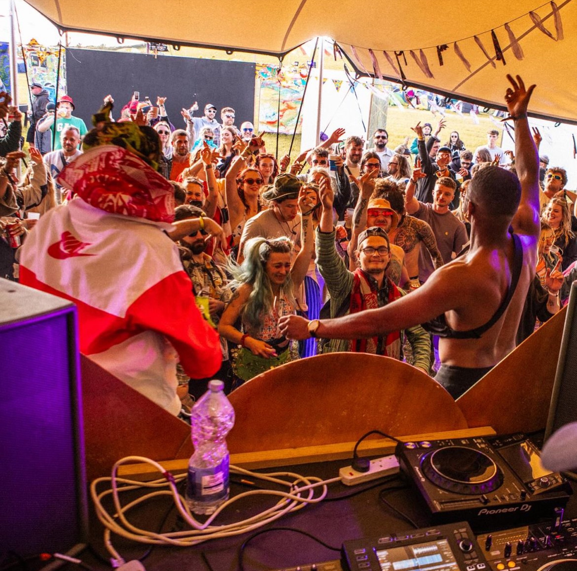 DJ playing to a packed crowd under a stretch tent